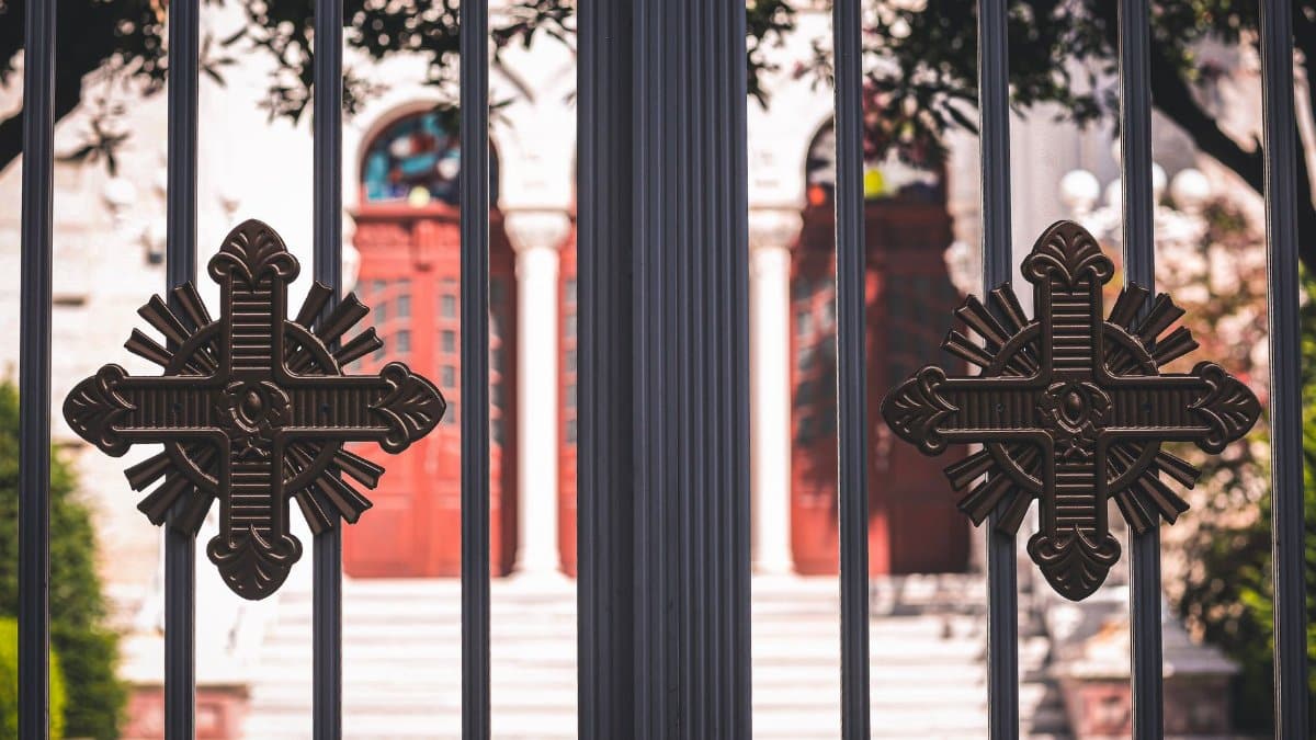 Close-up of a church entrance featuring ornamental metal gates with decorative crosses.