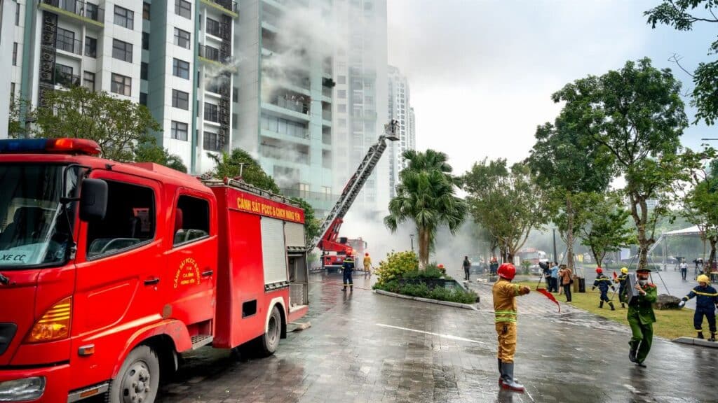 Firefighting operation at a high-rise apartment building, firefighters and trucks in action.