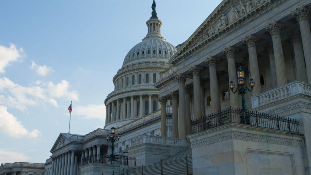 Classic view of the historic US Capitol Building in Washington, DC, with a clear blue sky.