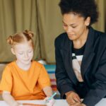 Child in colorful classroom learning with attentive teacher, fostering education and growth.
