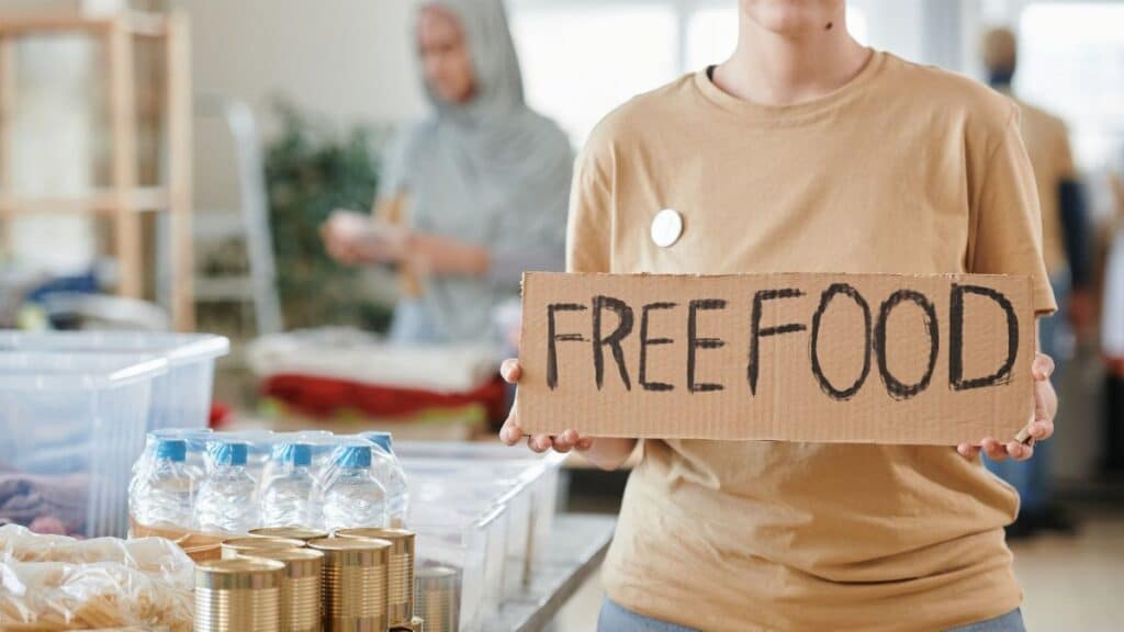 Volunteer holding a free food sign at a donation center, promoting charity and aid.