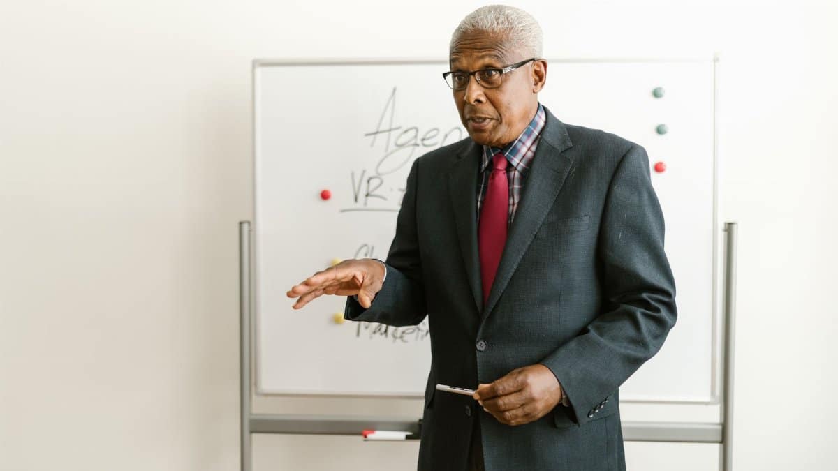 Elderly businessman presenting with a whiteboard in an office setting.