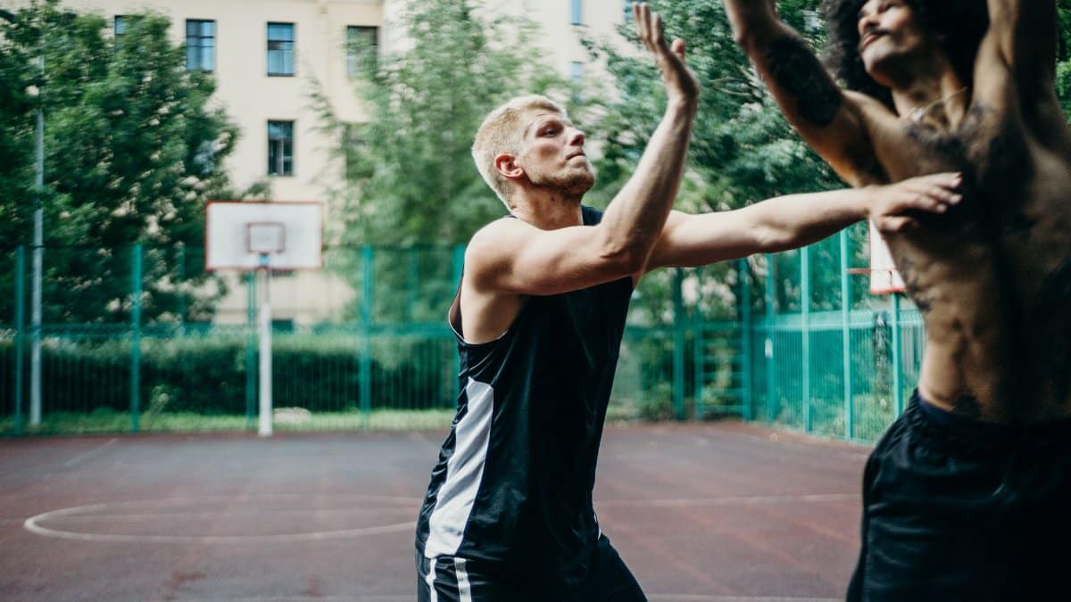 Two men playing competitive basketball on an outdoor court, showcasing action and intensity.
