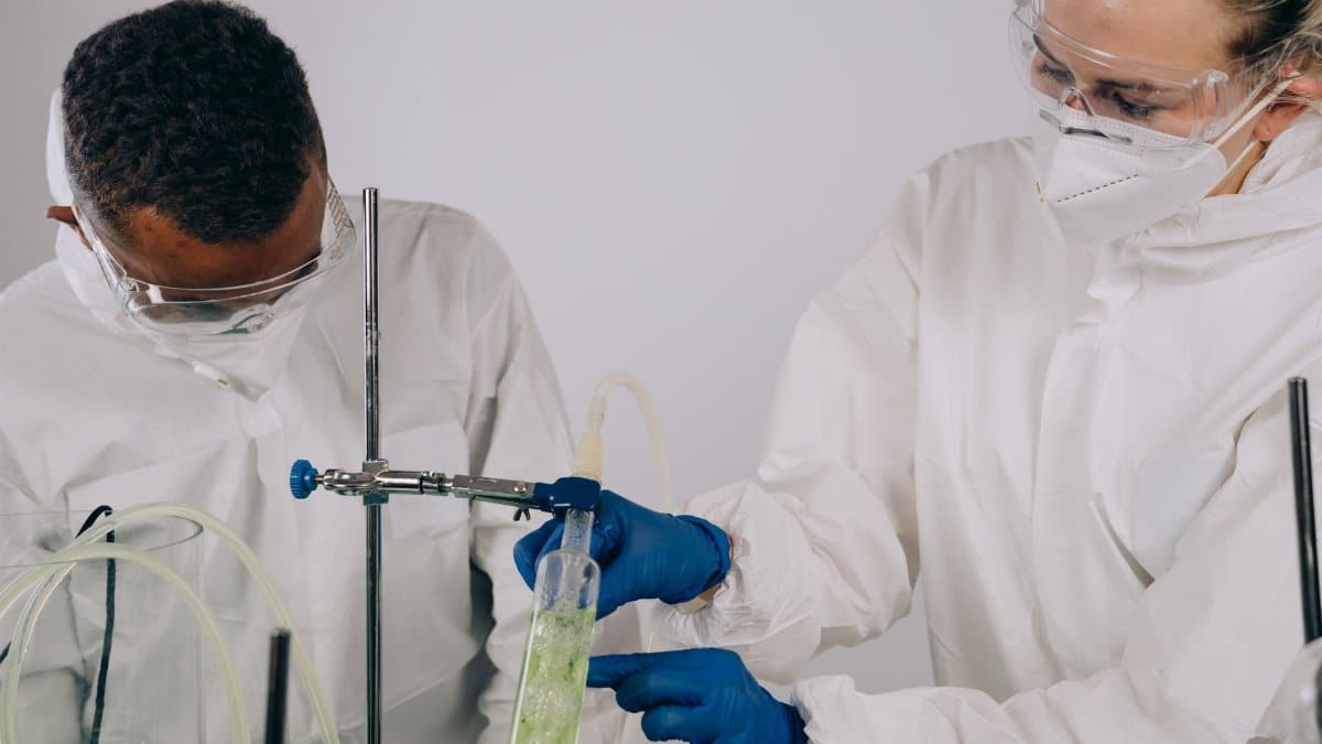 Two scientists in lab coats and protective gear conducting an experiment.