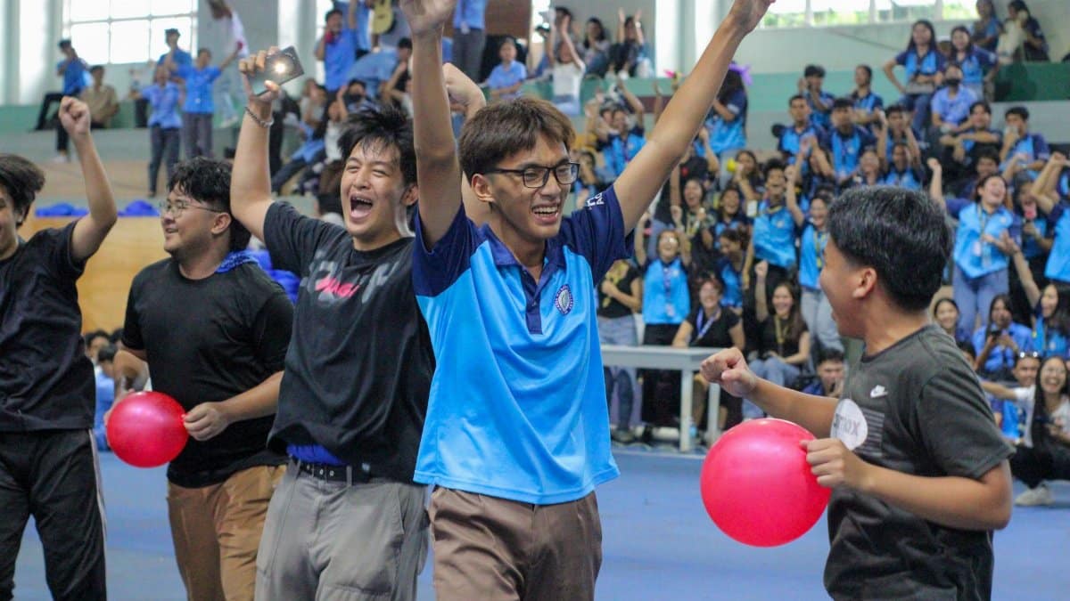 Group of young adults celebrating indoors at a team event with balloons and applause.