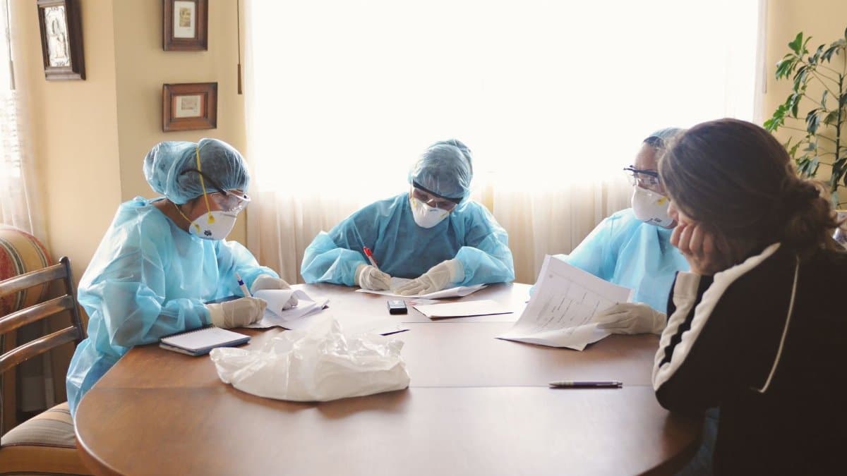 Medical team in protective equipment discussing at a table indoors.