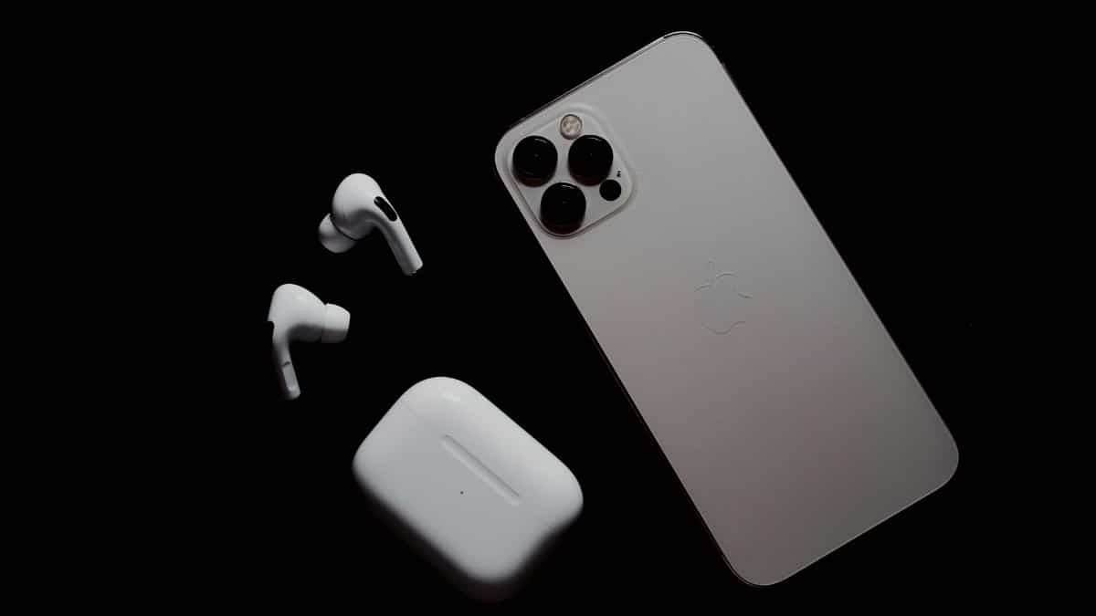 Close-up of smartphone and wireless earbuds on a dark surface, showcasing modern tech gadgets.