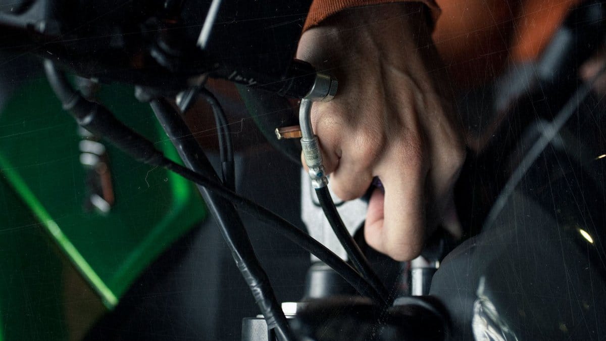 A detailed close-up of a hand adjusting motorcycle cables, showcasing technical maintenance.