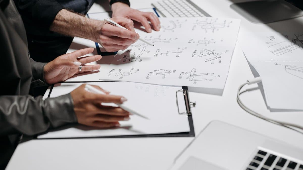 Team members analyzing technical schematics on office workspace. Ideal for business and engineering concepts.
