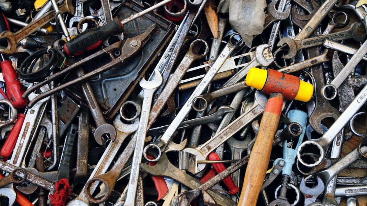 Close-up view of various tools including wrenches and a hammer, providing a cluttered yet organized look.