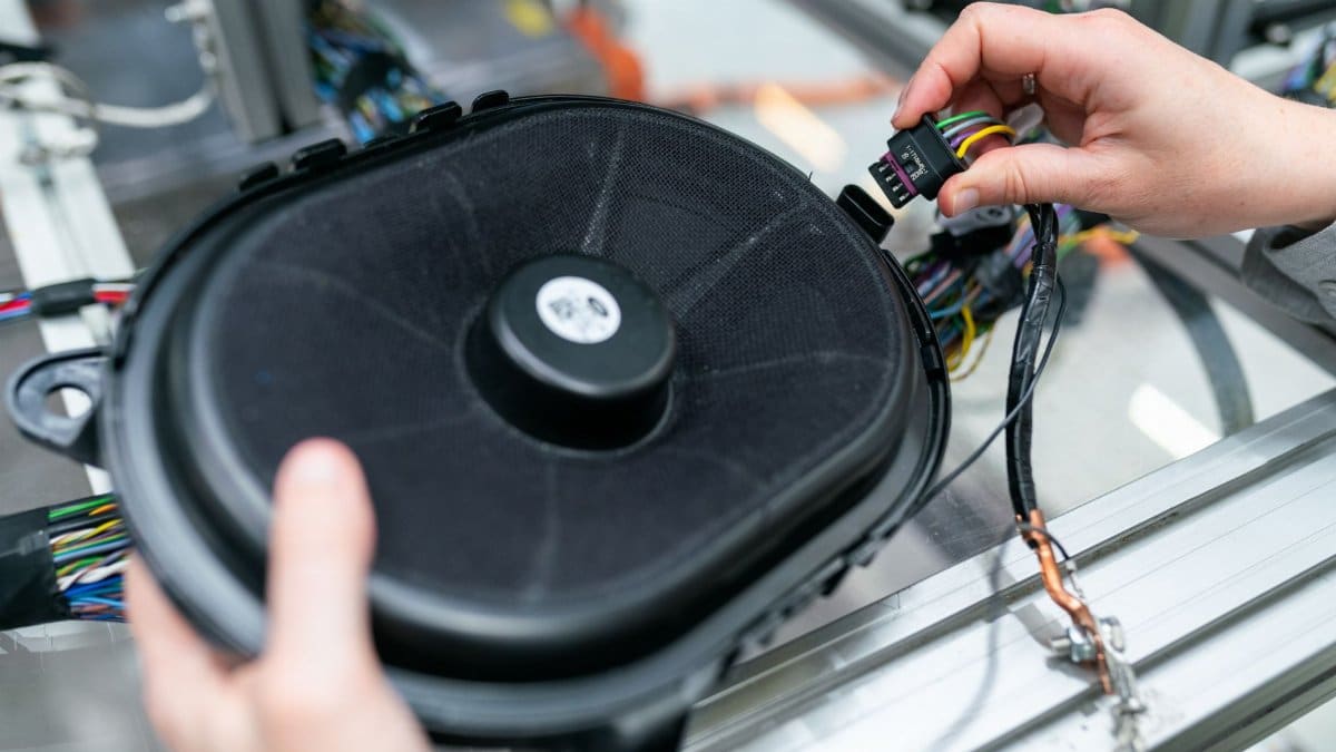 Close-up of an engineer working on a sound system speaker assembly in a workshop.
