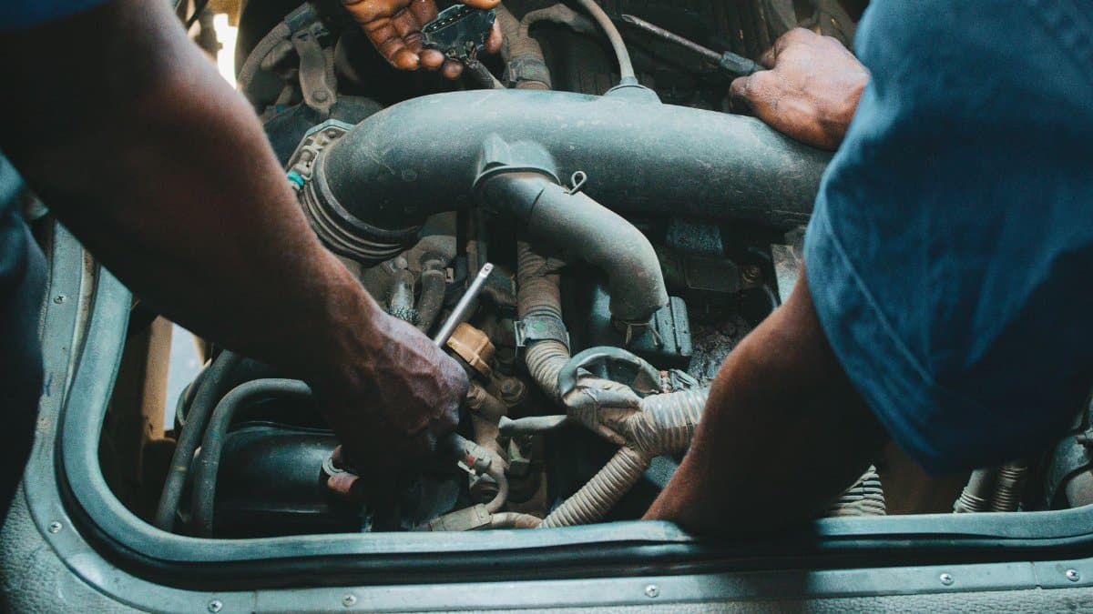 Auto mechanics repairing an engine in a Nigerian workshop. Close-up hands and tools.