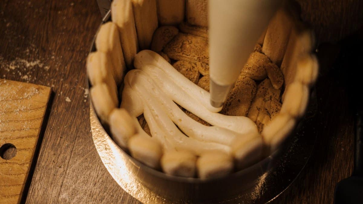 Close-up of cream being piped onto a biscuit base for a cake, ideal for home baking inspiration.