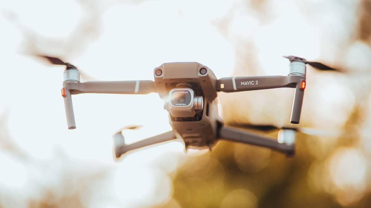 A detailed close-up of a DJI Mavic 2 drone flying outdoors in golden light.