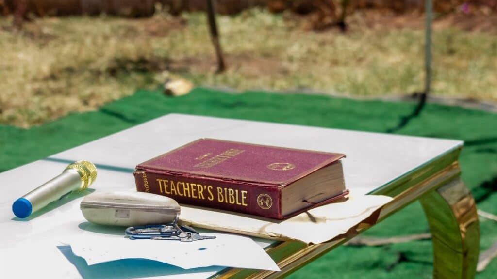 Outdoor table setup with a Teacher's Bible and microphone. Ideal for educational or religious themes.