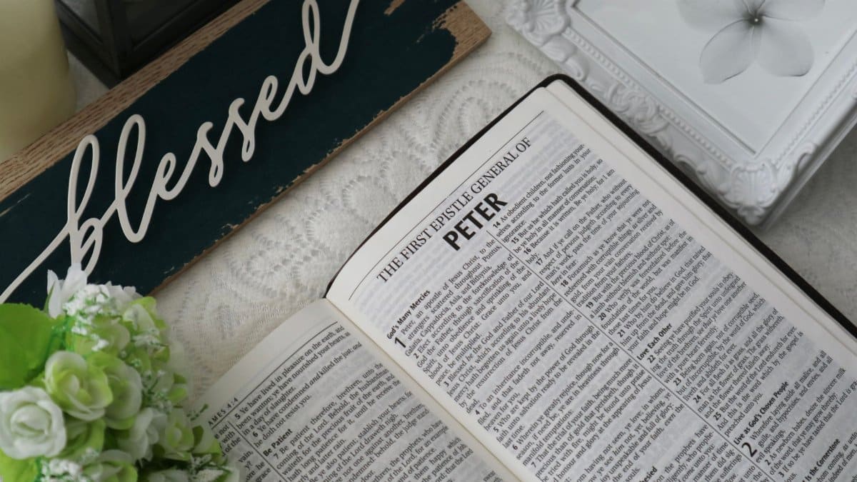 Top view of an open Bible with a 'blessed' sign and floral decor, conveying a serene and spiritual atmosphere.