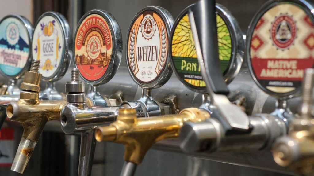 Close-up of craft beer taps with diverse labels in a bar setting. Ideal for beverages and brewery themes.