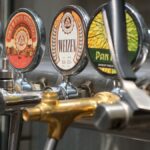 Close-up of craft beer taps with diverse labels in a bar setting. Ideal for beverages and brewery themes.