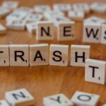 Close-up of wooden letter tiles spelling out Trash TV News on a table.