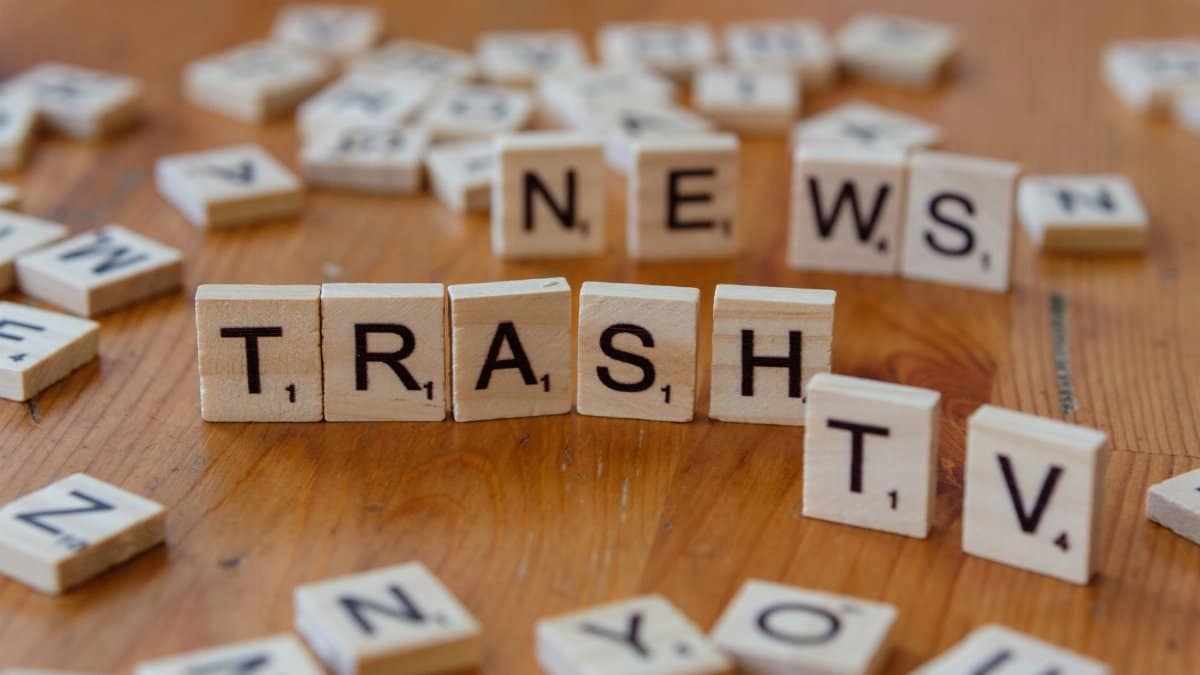 Close-up of wooden letter tiles spelling out Trash TV News on a table.