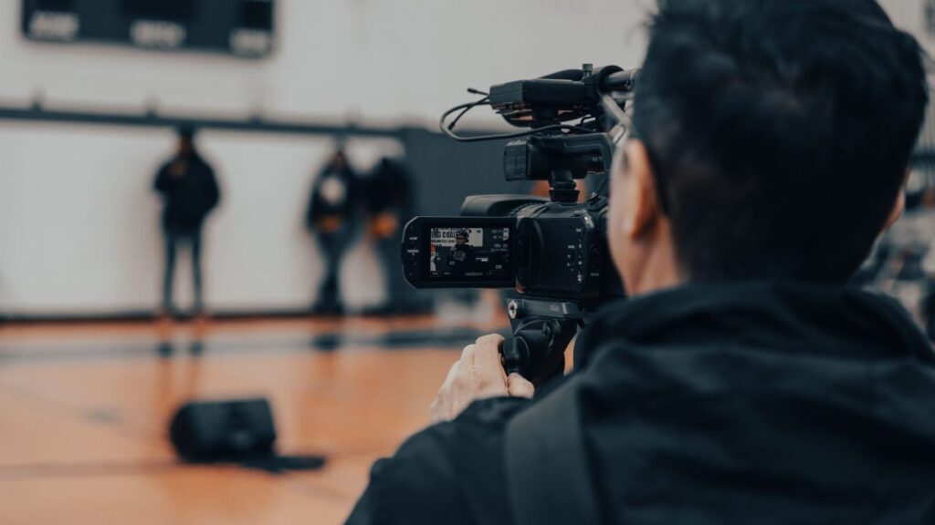 Back view of a cameraman filming an indoor event in Seattle with professional equipment.