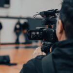 Back view of a cameraman filming an indoor event in Seattle with professional equipment.