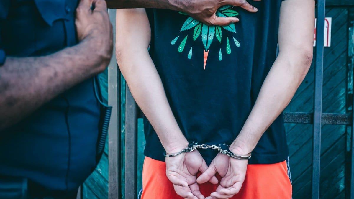 Close-up of a handcuffed person under arrest by a police officer outdoors.