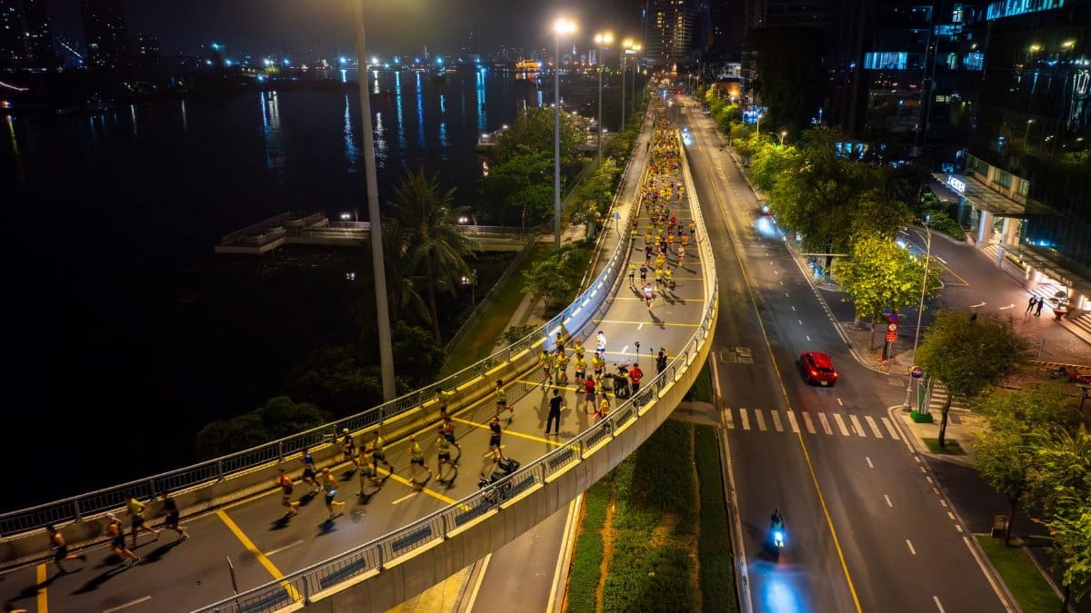 Aerial view of a bustling night marathon on a city bridge with vibrant lights.