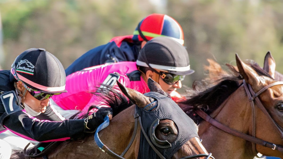 Close-up action shot of horse racing with jockeys focused and intense.