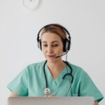 A female doctor in scrubs using a laptop for a virtual consultation, enhancing telemedicine.