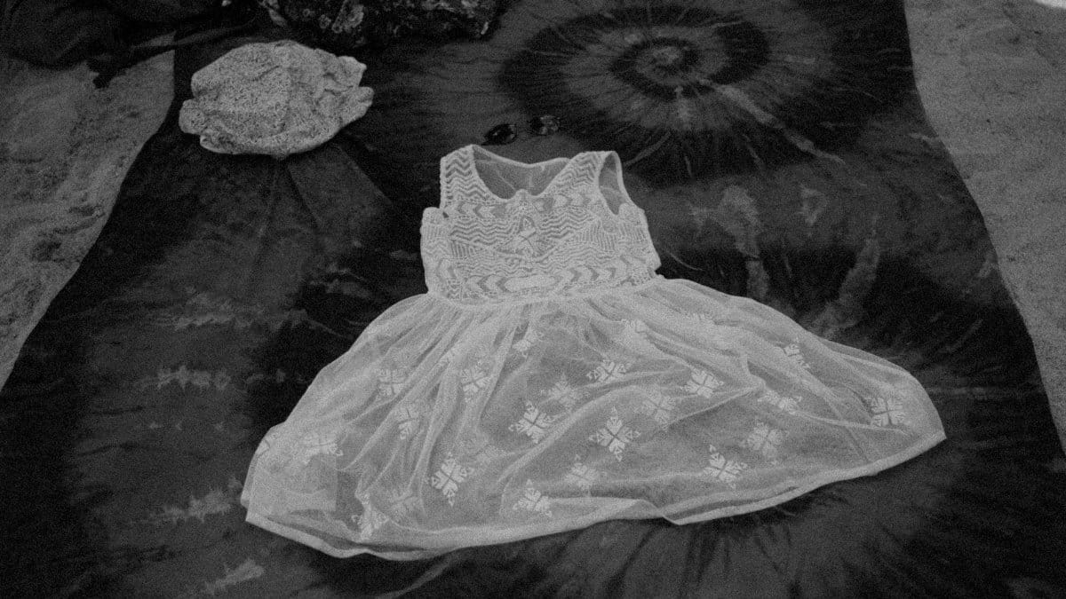 A stylish white lace dress displayed on a tie-dye blanket, exuding fashion and elegance.