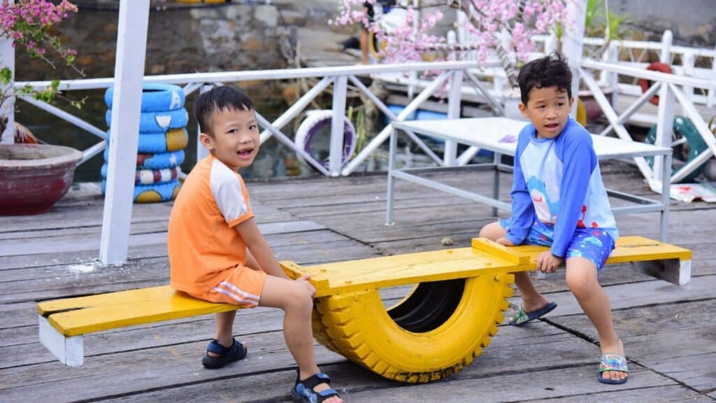 Two children playing on a colorful seesaw outdoors. Fun and joy on a bright sunny day.