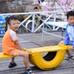 Two children playing on a colorful seesaw outdoors. Fun and joy on a bright sunny day.