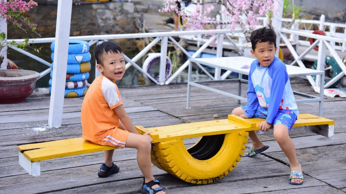 Two children playing on a colorful seesaw outdoors. Fun and joy on a bright sunny day.