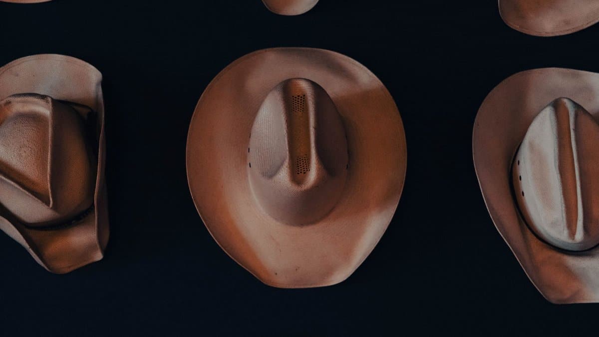 Artistic display of vintage cowboy hats in an overhead view, showcasing patterns in warm tones.