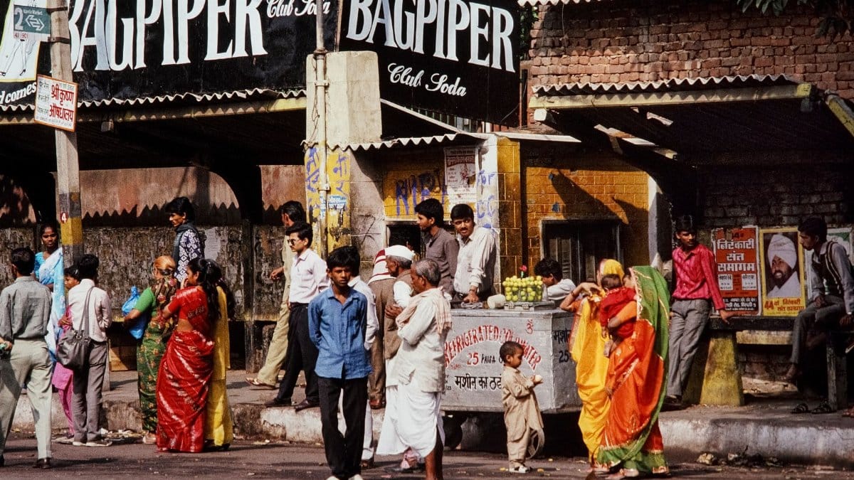 A bustling street scene in India with people gathered around a refreshment stand.