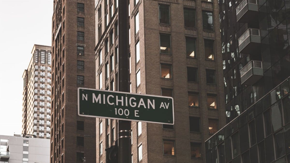 Low angle view of Michigan Avenue sign amidst towering Chicago skyscrapers.