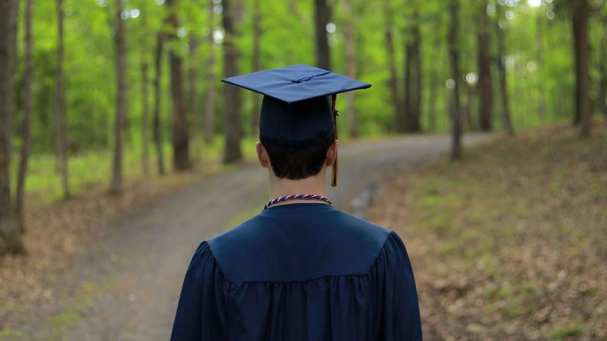 Graduate walking through a serene forest path, symbolizing new beginnings.
