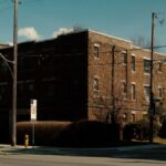 Street view of brick apartment building with blue sky and modern backdrop.
