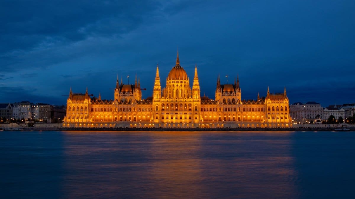 Majestic view of the illuminated Hungarian Parliament Building on the Danube River at night.