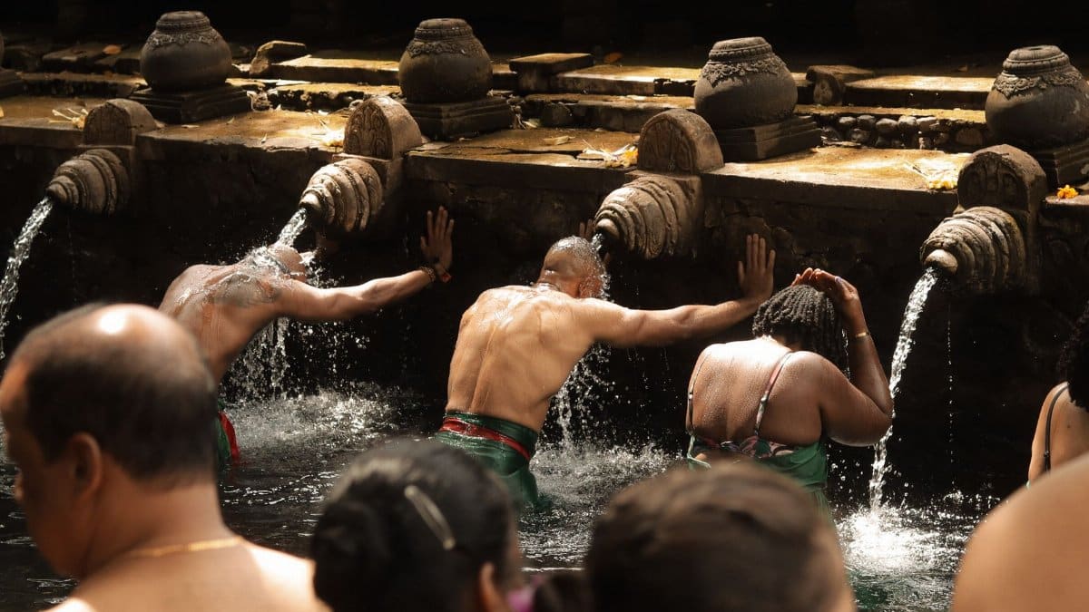 People engage in a traditional water purification ritual at a sacred site, symbolizing spiritual cleansing.