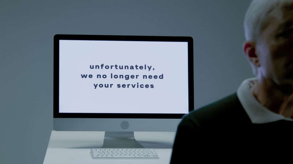 A computer screen displays a termination message, indicating job loss or unemployment.