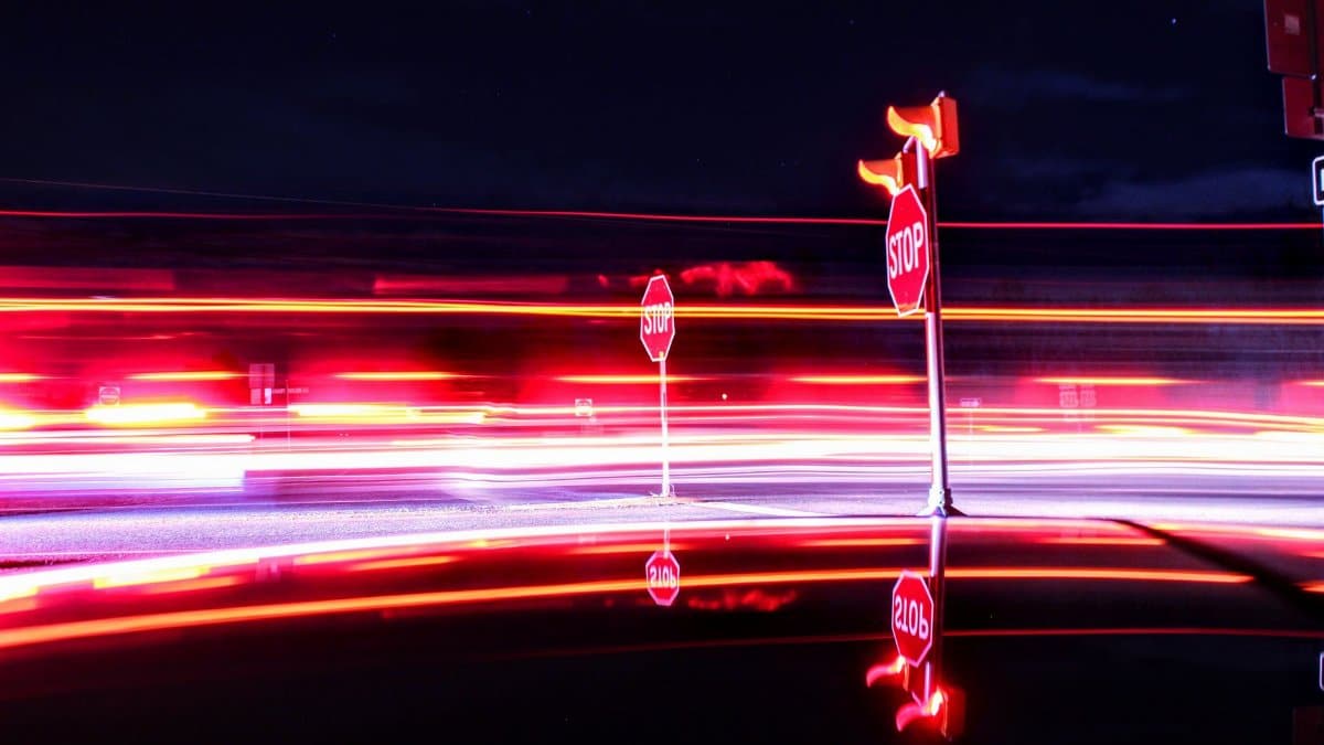 Vibrant light trails with stop signs in Virginia symbolize motion and pause, captured in long exposure.