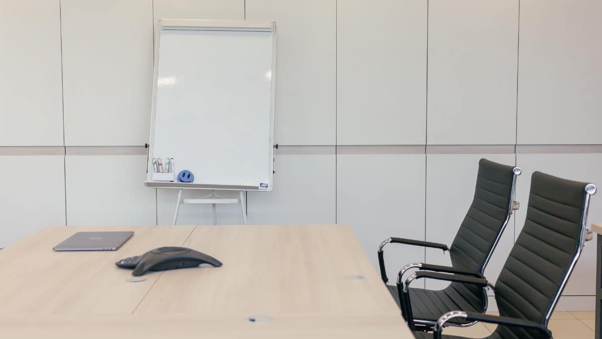 Sleek conference room with chairs, table, and whiteboard ready for a meeting.