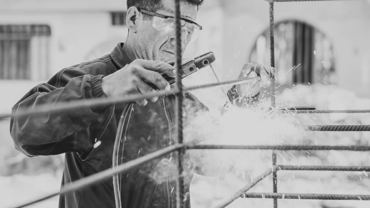 Welder in protective gear working on a metal frame at a construction site in Peru.