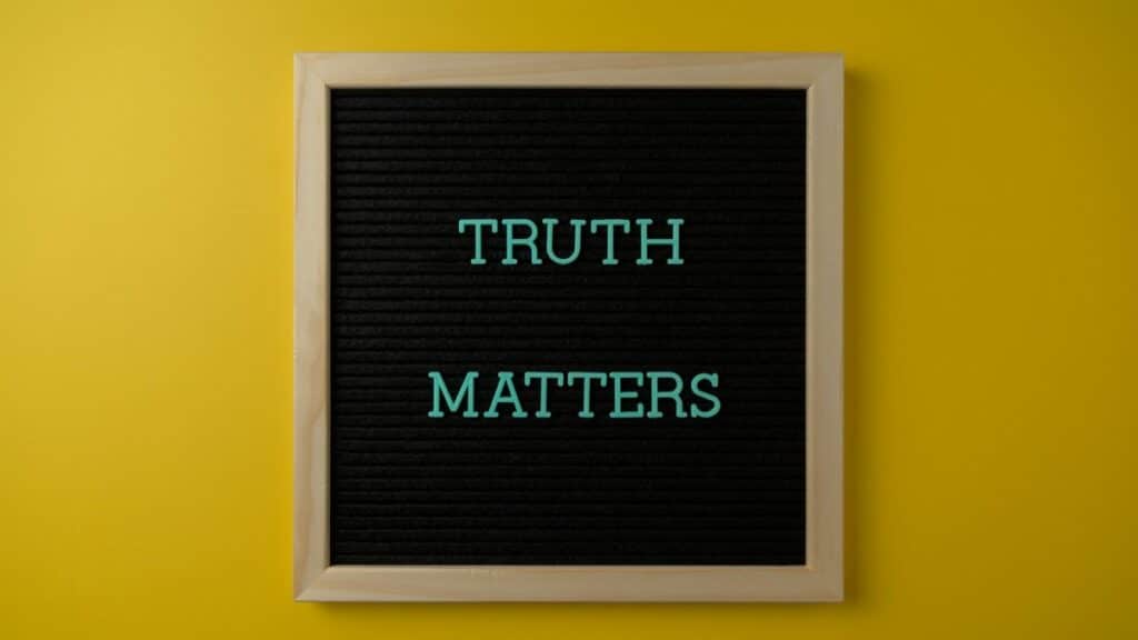Close-up of black letter board with 'Truth Matters' message on yellow background.