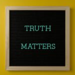 Close-up of black letter board with 'Truth Matters' message on yellow background.