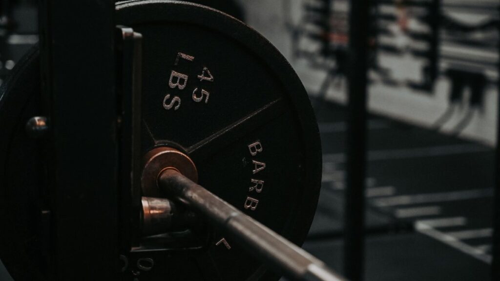Detailed close-up of a heavy barbell loaded with a 45 lbs weight plate in a gym setting.