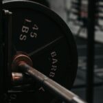 Detailed close-up of a heavy barbell loaded with a 45 lbs weight plate in a gym setting.