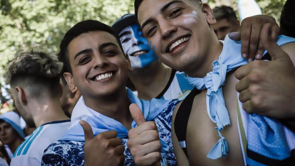 Excited fans in Buenos Aires showing enthusiasm with thumbs up and face paint.
